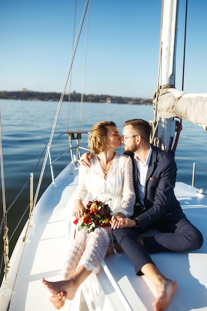 一緒に海で屋外の結婚式の日にヨットで美しい結婚式のカップル
