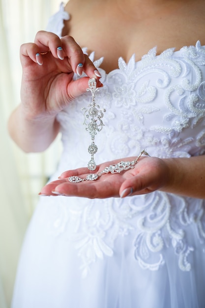 Beautiful wedding earrings in the hands of the bride on their wedding day