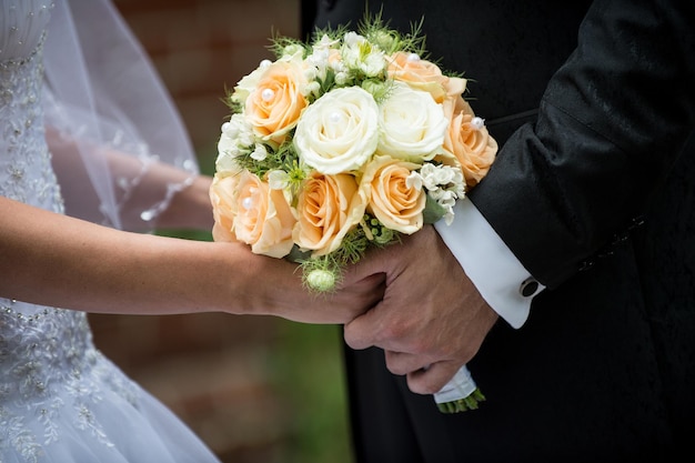 Bellissimo bouquet di rose da sposa nelle mani della sposa e dell'uomo