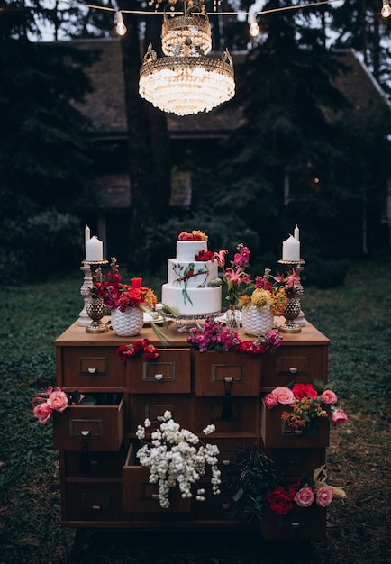 Una bellissima torta nuziale a tre livelli decorata con uccelli, fiori rosa e rami con foglie verdi in stile rustico. dessert festivo concetto di matrimonio.