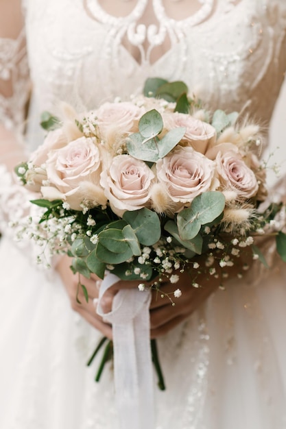 Beautiful wedding white bouquet of roses in the hands of the bride