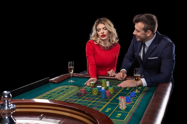 Beautiful and well dressed couple playing roulette in the casino