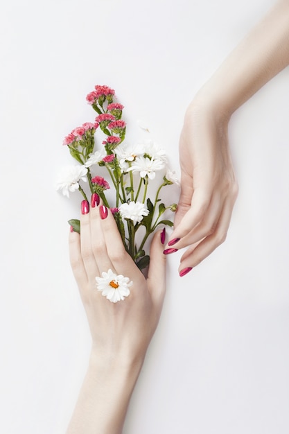 Beautiful well-groomed hands wild flowers on table