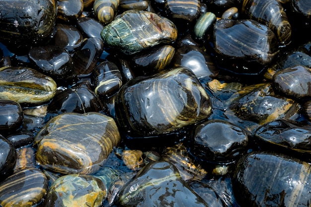 Beautiful wet black stones at Koh Hin Ngam in summer time concept travel, holiday.