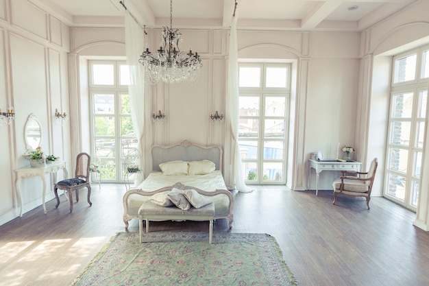 Красивый белый светлый чистый интерьер спальни в роскошном стиле барокко.