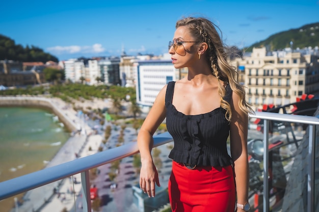 Beautiful white Caucasian woman standing on the balcony of the hotel room with a sea view