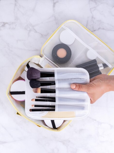 A beautiful white cosmetic bag with the necessary products for the care of women's skin Cosmetics shampoo creams makeup brushes in a cosmetic bag against the backdrop of a beautiful women's room