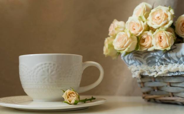 Beautiful white cup and tea roses in a basket Image with selective focus