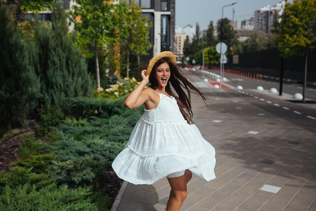 Beautiful in a white dress poses on the street