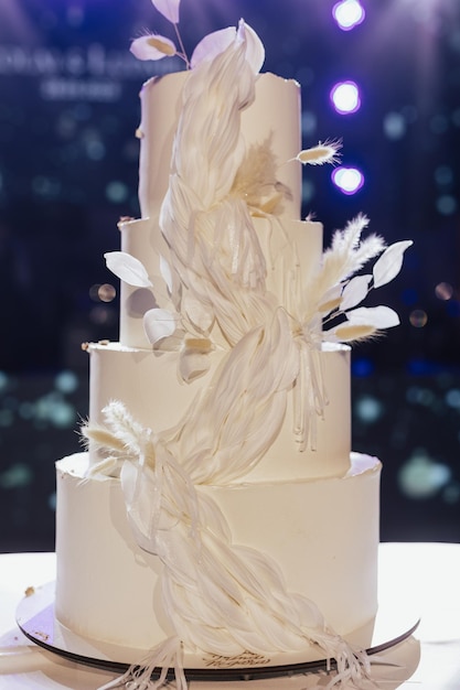 Foto bella torta nuziale bianca a quattro livelli decorata con fiori bianchi