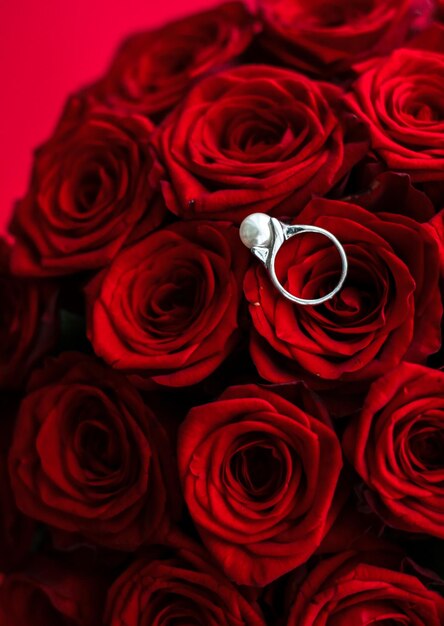 Beautiful white gold pearl ring and bouquet of red roses luxury jewelry love gift on Valentines Day and romantic holidays