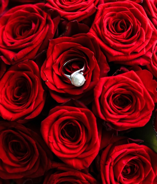 美しいホワイト ゴールド パール リングと赤いバラの花束高級ジュエリー バレンタインデーやロマンチックな休日のギフトが大好き