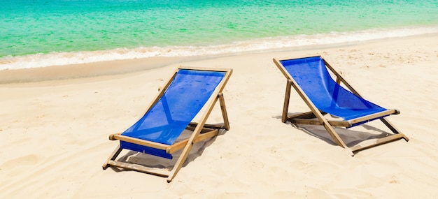 Beautiful white sand beach. Chairs on foreground, fishing boats on background. Landscape of Vietnam