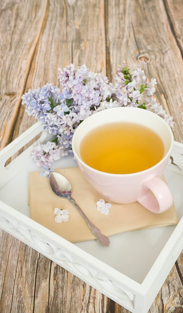 Beautiful white tray with a cup of tea and a branch of lilac