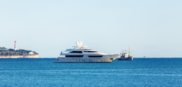 A beautiful white twodeck yacht stands in the Gelendzhik Bay against the backdrop of the city