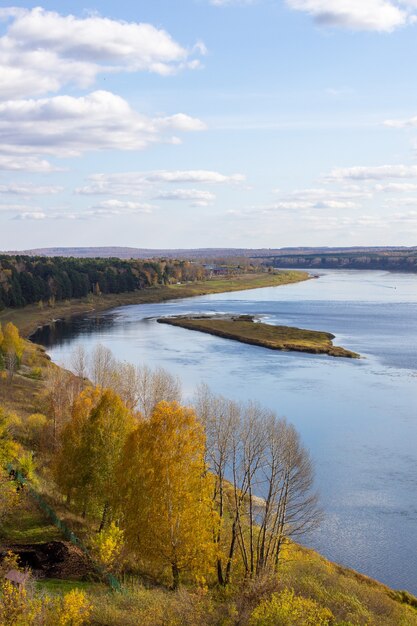 Красивая широкая река в осеннем лесу в тихом и спокойном месте Отражение неба.