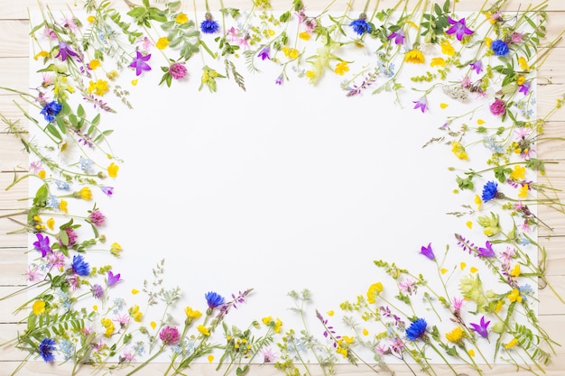 Photo beautiful wild flowers on white sheet on wooden background