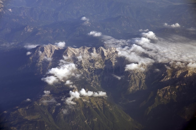 Beautiful window view of blue sky, fluffy clouds and Alps mountains from passenger seat on airplane.