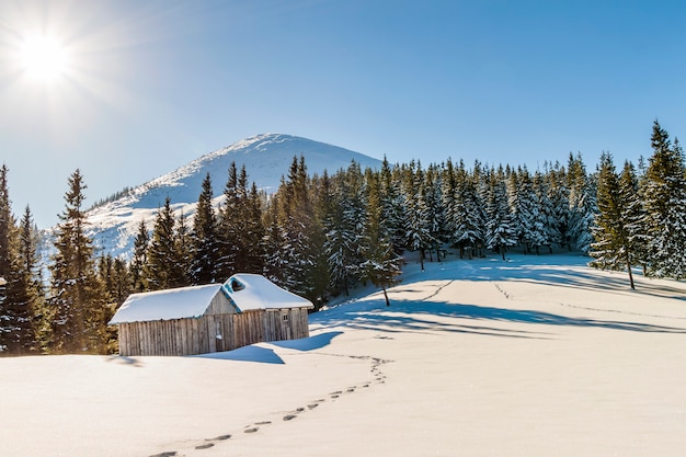 草原と小さな小さな家の雪道と山の美しい冬の風景。幸せな新年のお祝いのコンセプト。