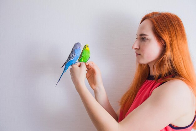 The beautiful woman admires her beautiful parrots