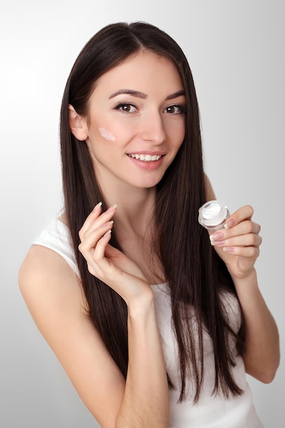 Bella donna che applica crema cosmetica per il viso