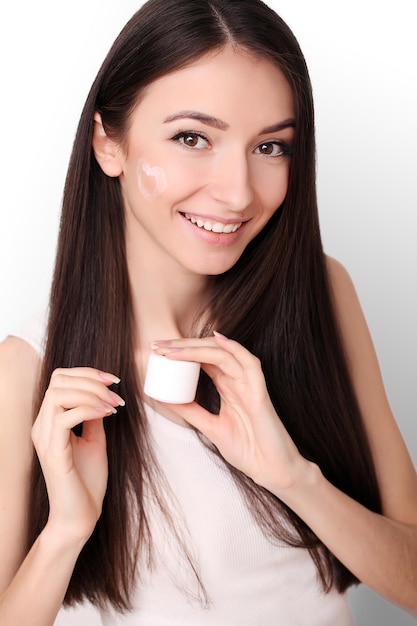 Bella donna che applica crema cosmetica per il viso