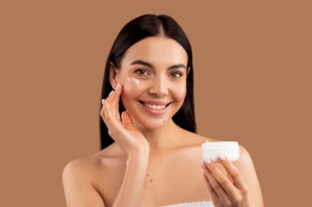 Photo beautiful woman applying facial cream on her skin