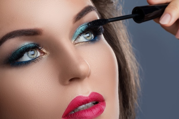 Beautiful woman applying mascara on her lashes