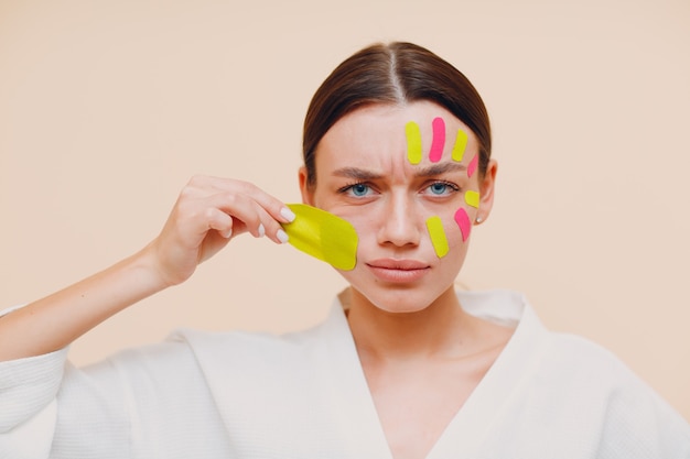 Beautiful woman applying tape lifting treatment on face removing