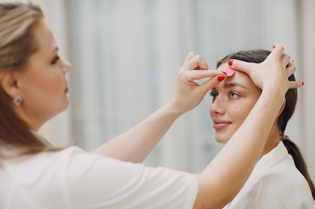 Beautiful woman applying tape lifting treatment on face