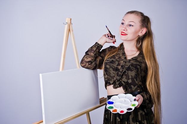 Beautiful woman artist painter with brushes and oil canvas posing  isolated on white.