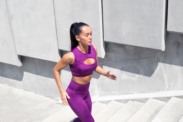 Beautiful woman athlete runs up the stairs