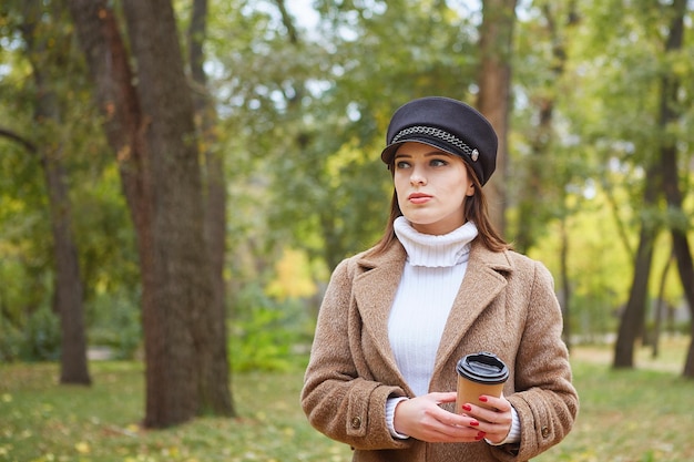 コーヒーと秋の公園で美しい女性