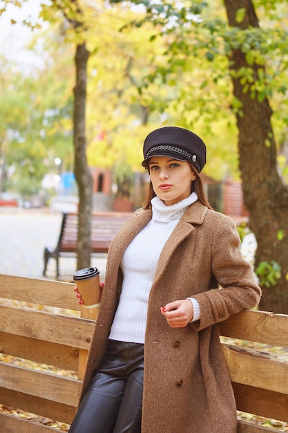 Beautiful woman in autumn park with coffee