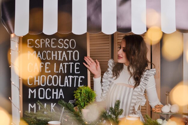 beautiful woman barista in striped apron holds coffee cup in hand New year showcase