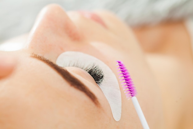 Beautiful Woman in a beauty salon. Eyelash extension procedure. Lashes close up