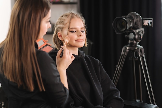 Beautiful woman beauty vlogger doing cosmetic makeup demonstration with her friend in studio