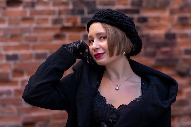 Beautiful woman in beret in retro style on a brick wall background