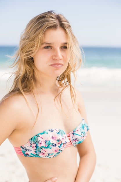 Bella donna in bikini in piedi sulla spiaggia