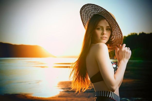 Beautiful woman in bikini on sunset background. Slim girl posing in a swimsuit