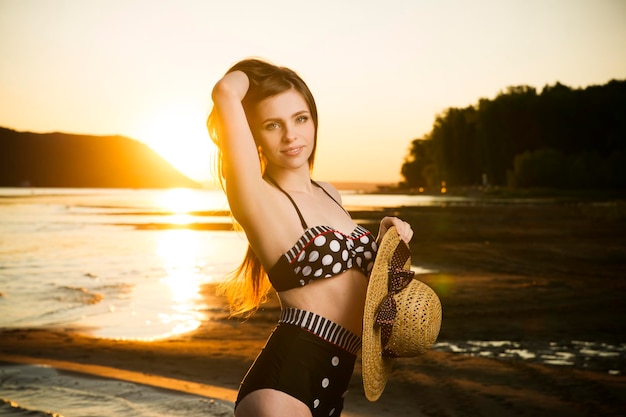 Beautiful woman in bikini on sunset background Slim girl posing in a swimsuit