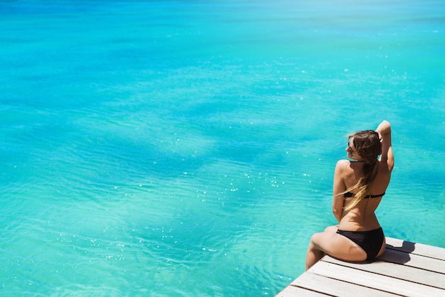 Beautiful woman in black bikini sunbathing enjoying wonderful ocean view