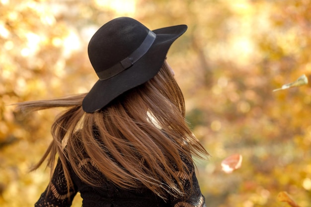 가을에 검은 드레스와 모자를 쓴 아름다운 여자