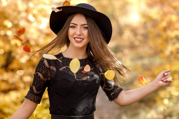 가을에 검은 드레스와 모자를 쓴 아름다운 여자