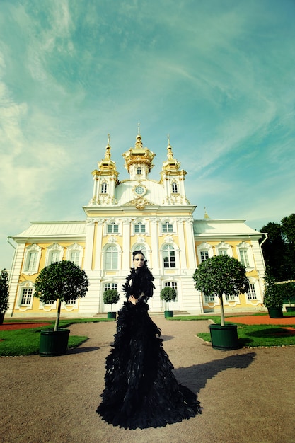 Beautiful woman in black dress posing next to the palace.