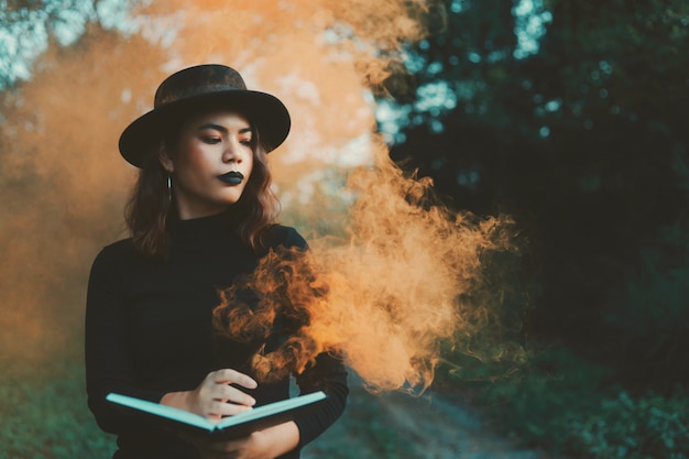 Beautiful woman in black dress standing in forest.