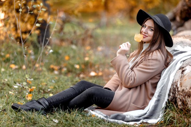 Beautiful woman in black hat sitting under big tree