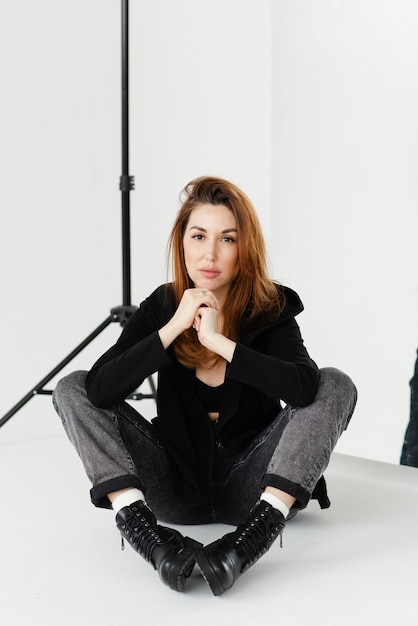 Beautiful woman in black shirt and jeans posing in studio