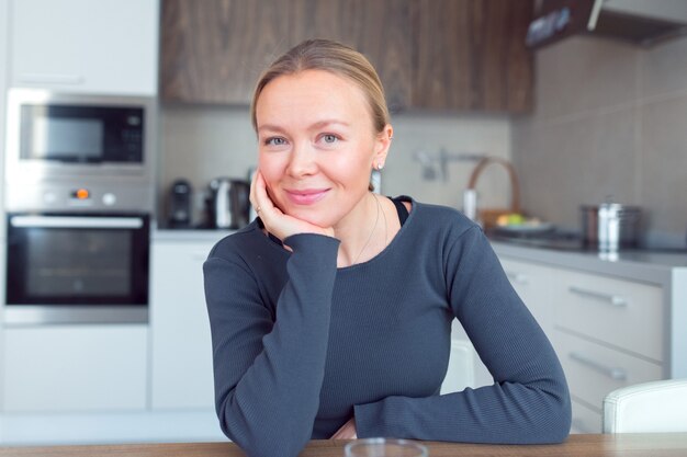 Beautiful woman blonde sit at table kitchen look