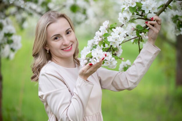 Красивая женщина в цветущем саду улыбается, наслаждаясь жизнью